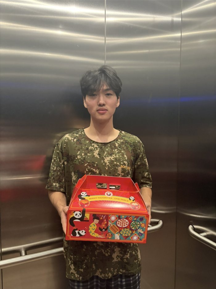 Brandon Lee holding a Panda Express family meal box in an elevator