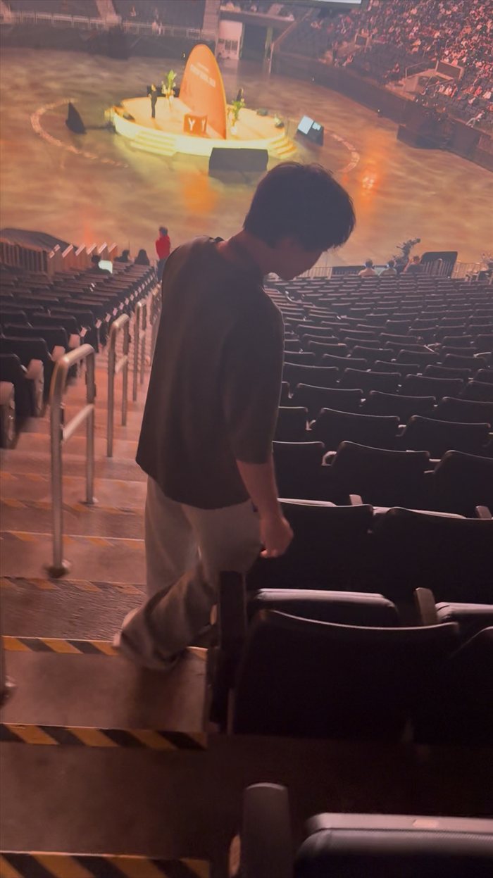 Brandon Lee walking down the arena steps at YC Startup School with the stage below